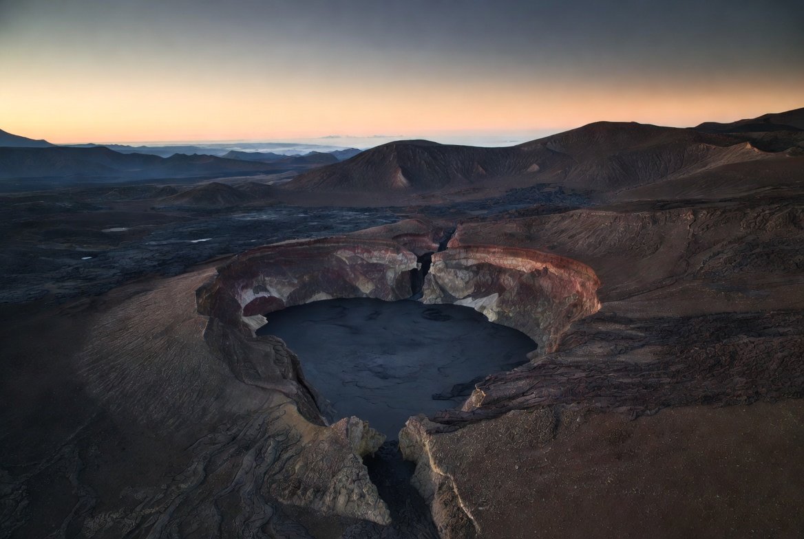 An aerial view of a drained volcanic lava lake at dusk.